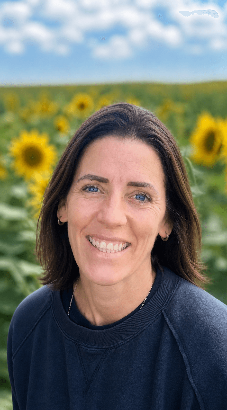 Tomi Kennedy, head and shoulders portrait in front of a sunflower field